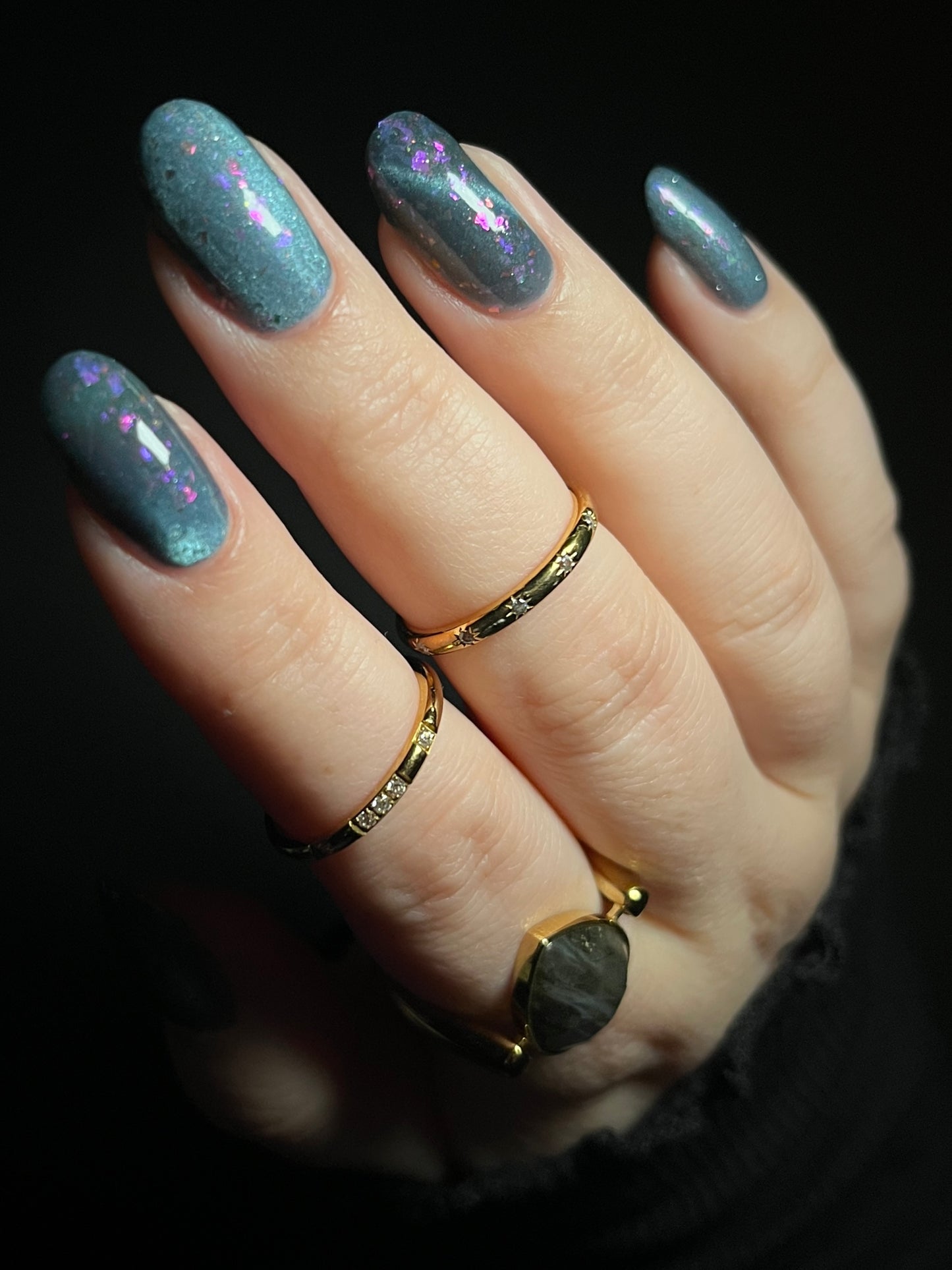 Hand with dusky gray blue magnetic nail polish with pink flakes. Opal Theory Polish Lagoon Nebula