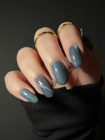 Hand with dusky gray blue magnetic nail polish with pink flakes. Opal Theory Polish Lagoon Nebula