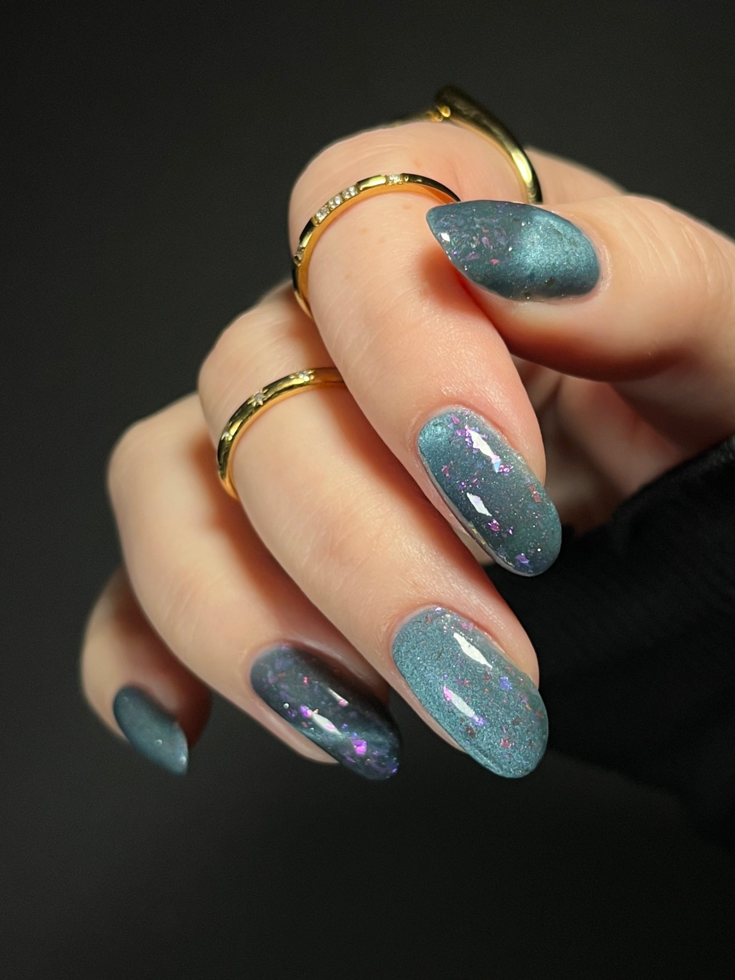 Hand with dusky blue magnetic nail polish with pink flakes. Opal Theory Polish Lagoon Nebula