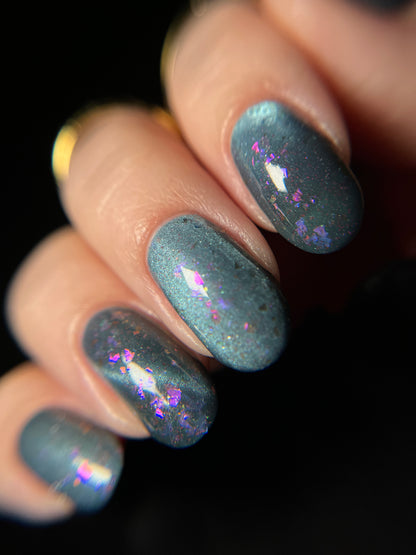 Hand with dusky gray blue magnetic nail polish with pink flakes. Opal Theory Polish Lagoon Nebula