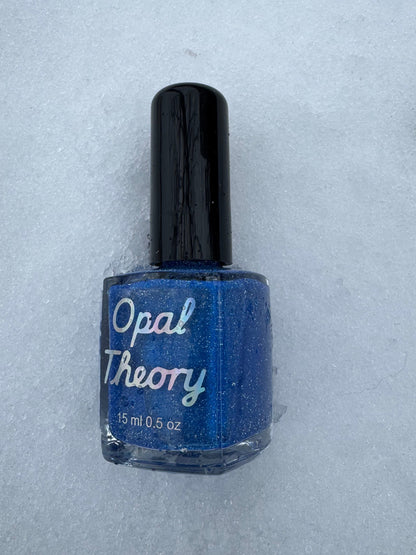 Blue nail polish bottle with 'Opal Theory' label on a snowy background