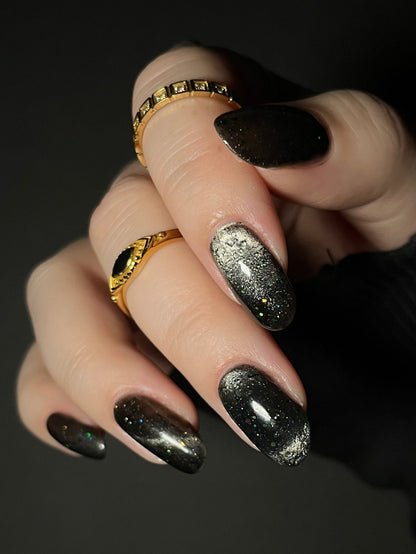 Close-up of a hand with black jelly nail polish with silver magnetic pigment and silver and black holo glitter. Opal Theory Polish Deep Field