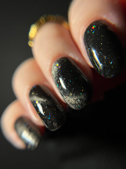 Close-up of a hand with black jelly nail polish with silver magnetic pigment and silver and black holo glitter. Opal Theory Polish Deep Field