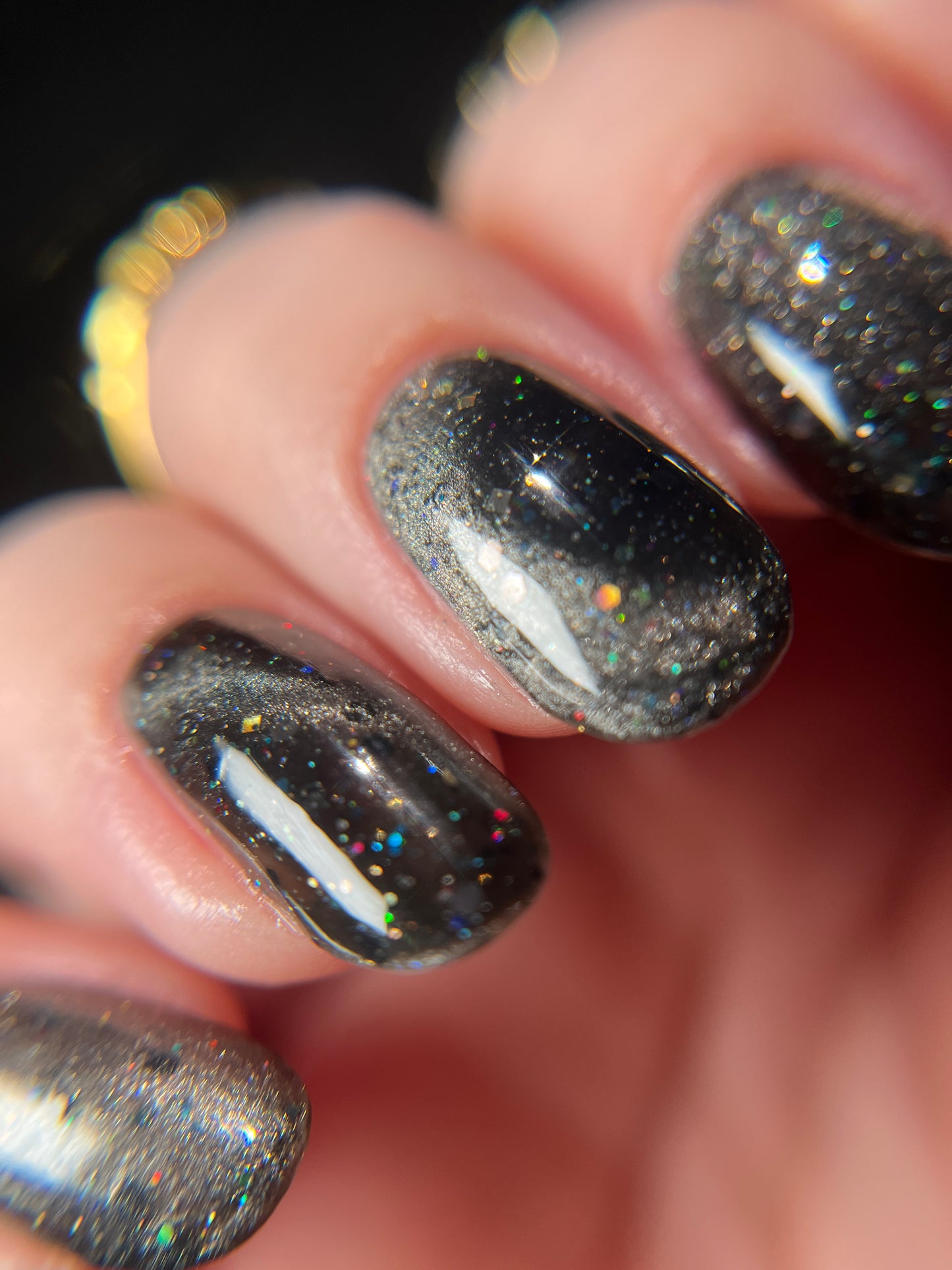 Close-up of a hand with black jelly nail polish with silver magnetic pigment and silver and black holo glitter. Opal Theory Polish Deep Field