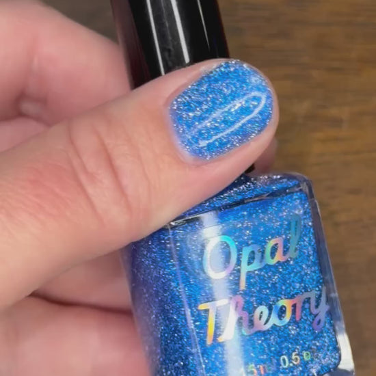 Hand holding a sparkly blue nail polish