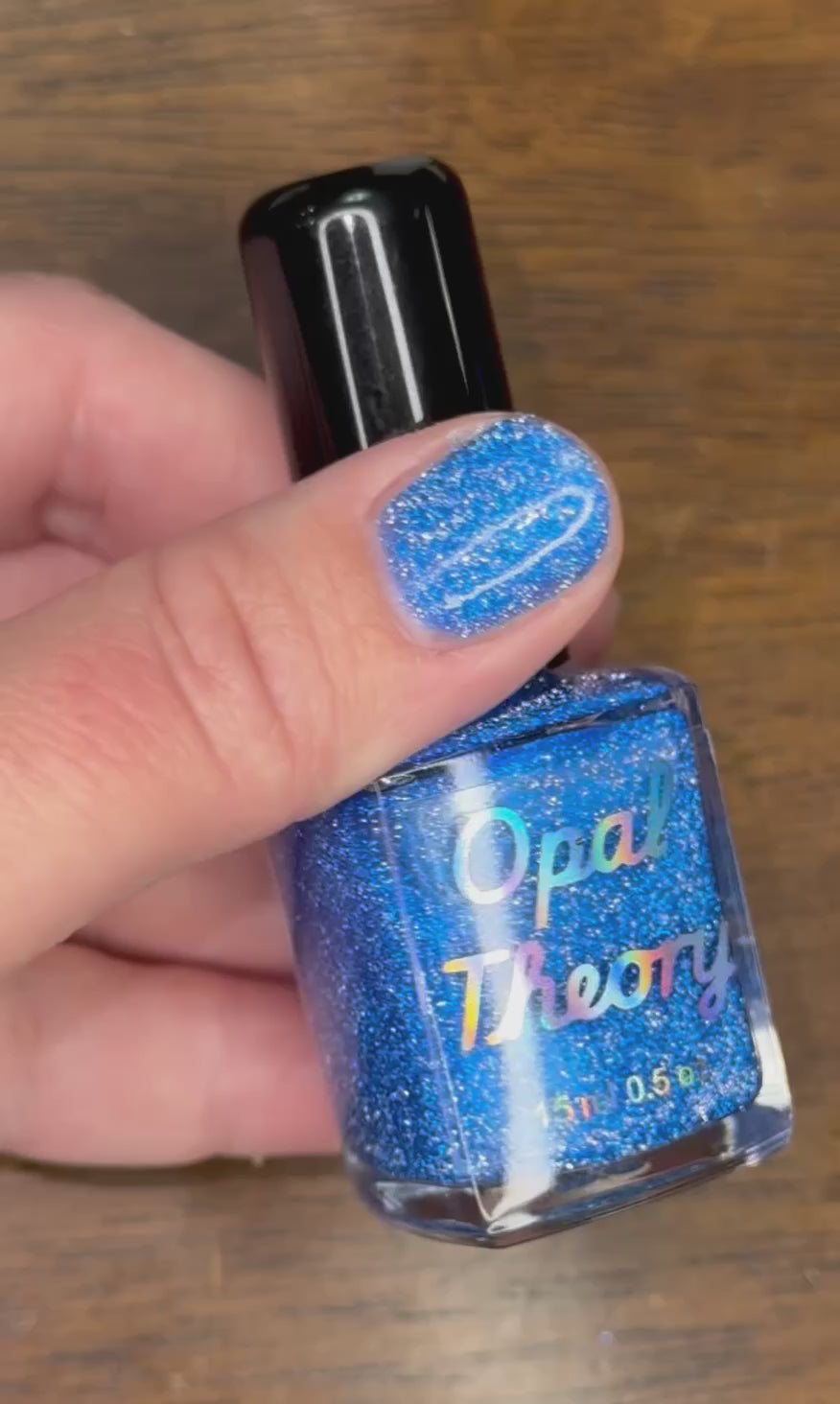 Hand holding a sparkly blue nail polish